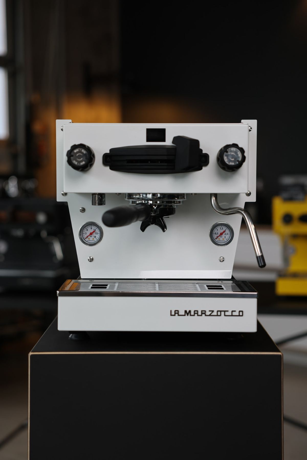 Weiße La Marzocco Linea Mini auf schwarzem Sockel
